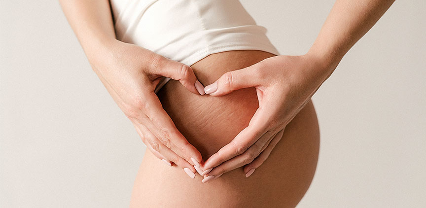 A woman holding her hands in a heart shape over her thigh