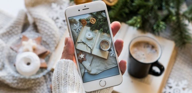 A woman holding an iPhone while taking a photo.