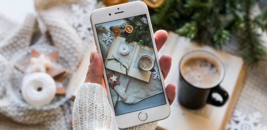 A woman holding an iPhone while taking a photo.