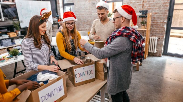 A group of employees filling up donation boxes, and wearing Santa hats