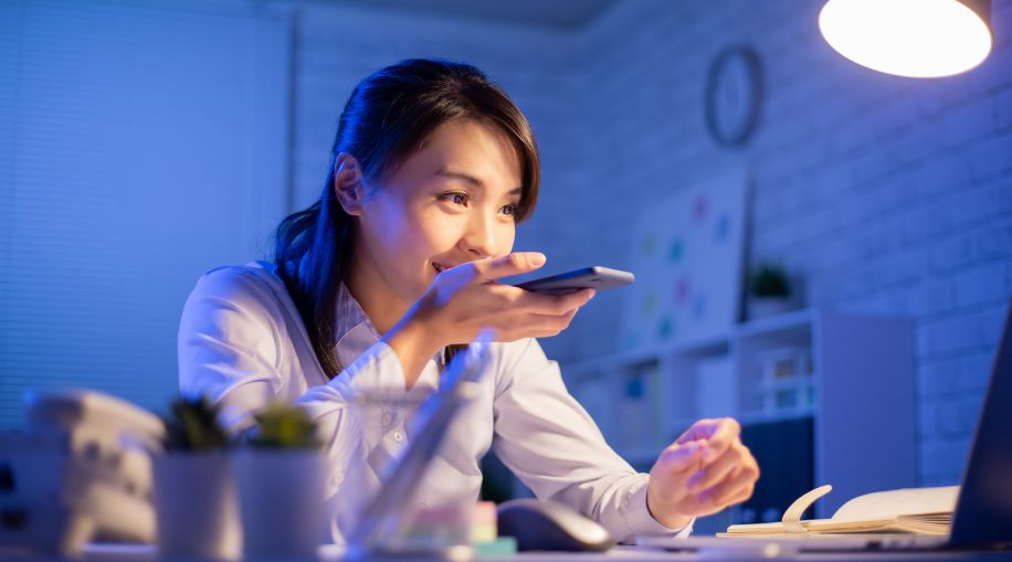 A woman holding a cell phone in front of her mouth and talking into it.