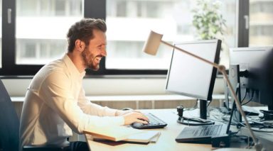 A man sitting at a desk, looking at a computer screen.