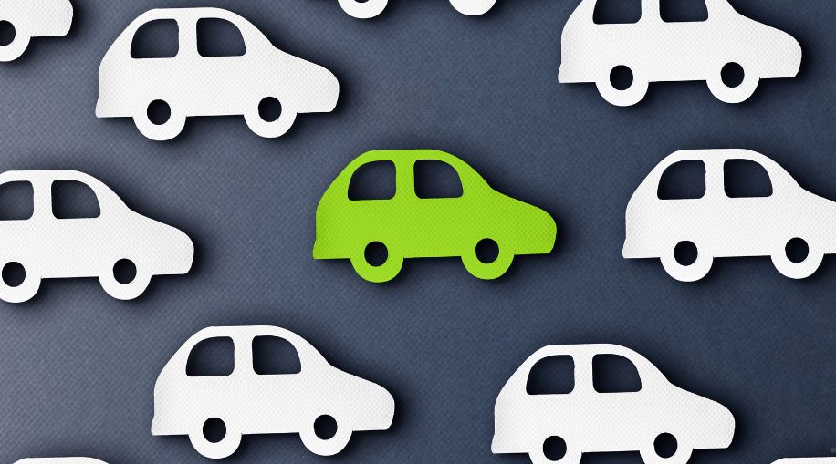 Paper cut outs of white and green cars on a grey background.